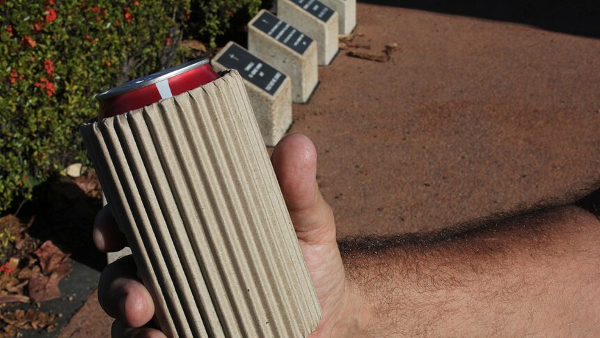 Man clutching a can with a cardboard stubby cooler wrapped around it