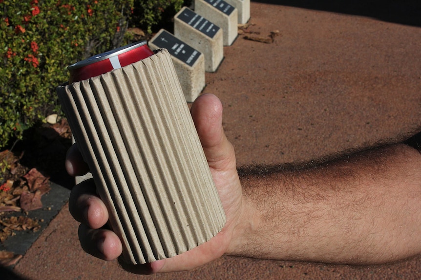 Man clutching a can with a cardboard stubby cooler wrapped around it