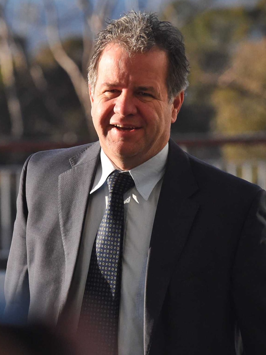 Dennis Jensen smiles at the camera while walking into Parliament House