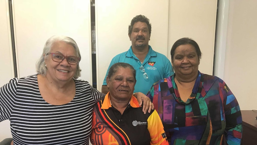 A group of four Aboriginal people smiling at the camera, three women and a man.