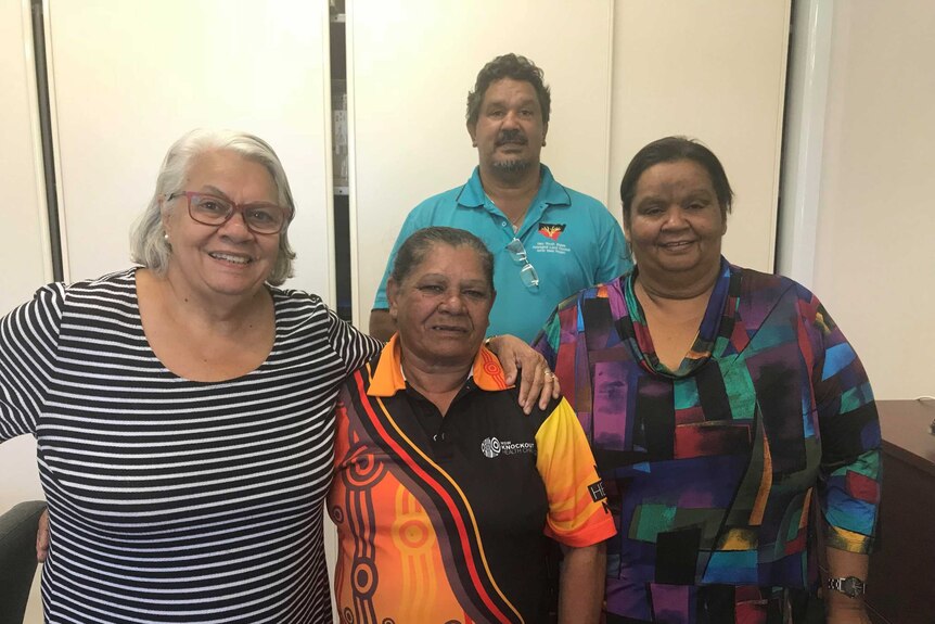 A group of four Aboriginal people smiling at the camera, three women and a man.