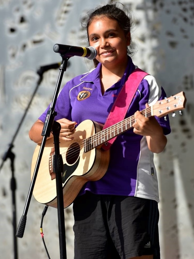 A young Indigenous woman plays a guitar.
