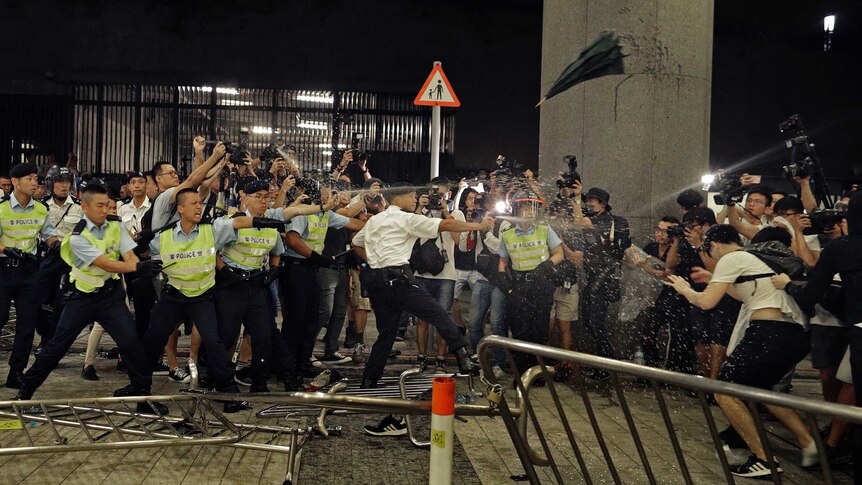 Police officers use pepper spray against protesters in a rally against an extradition law in Hong Kong.