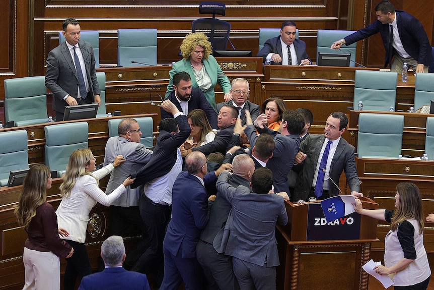 a group of politicians pile on and shove eachother in parliament. 
