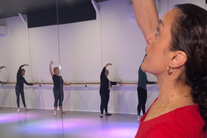 A woman's face looking up at her hand with several older women's reflection in mirrors.