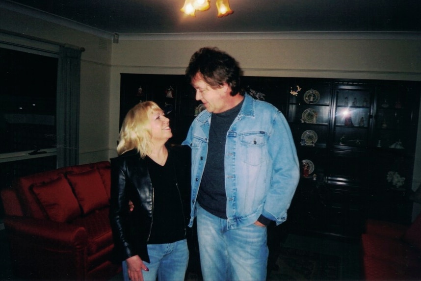 Terence and Christine Hodson stand together in their home, looking at eachother.