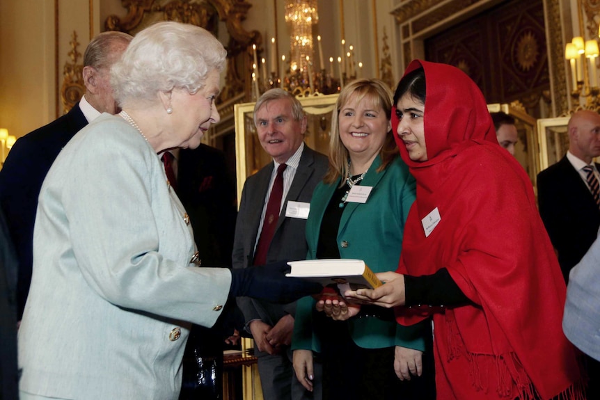 Malala Yousafzai gives a copy of her book to Queen Elizabeth II.