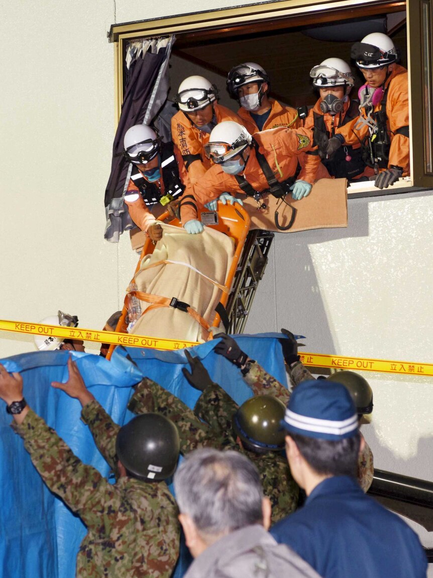 Rescue workers use a stretcher to carry a woman out the window of a house damaged by the earthquake.