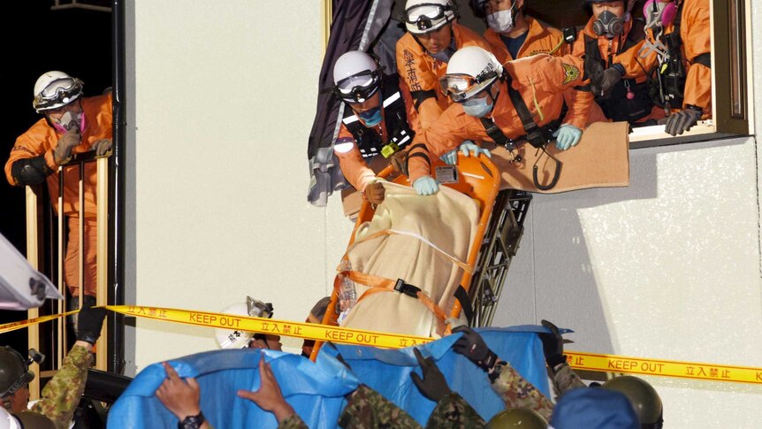 Rescue workers use a stretcher to carry a woman out the window of a house damaged by the earthquake.