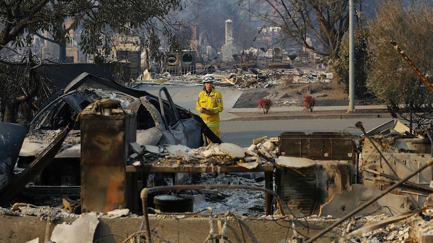 A firefighter, dressed in yellow, stands amongst the ruins of a Santa Rosa neighbourhood.