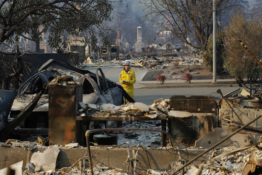 A firefighter, dressed in yellow, stands amongst the ruins of a Santa Rosa neighbourhood.