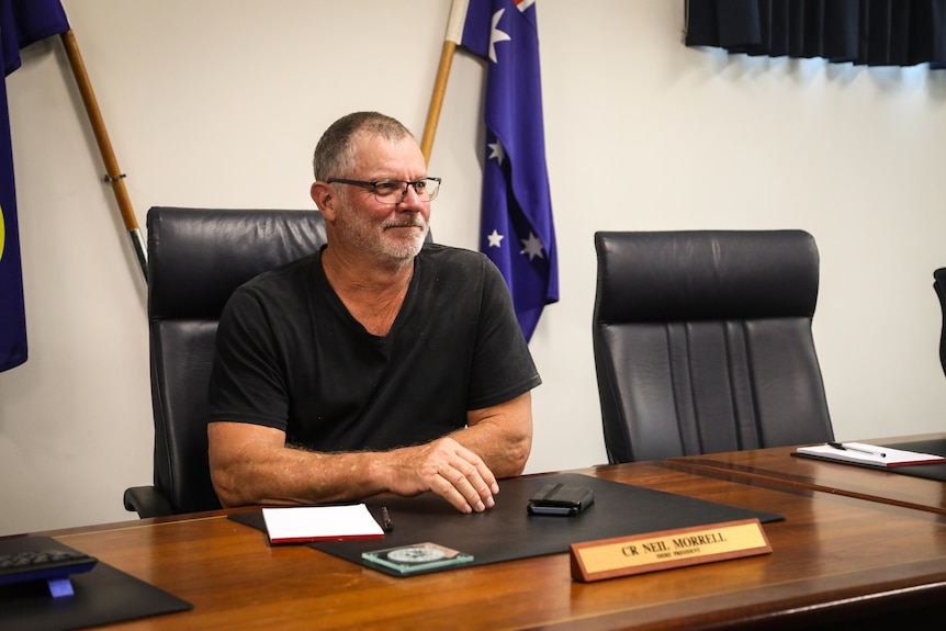 Neil Morrell sits in his mayoral office in front of Australian flags