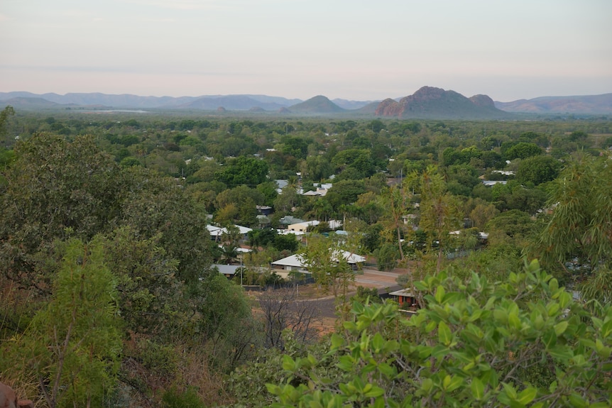 An aerial shot of an outback town with ranges behind it.