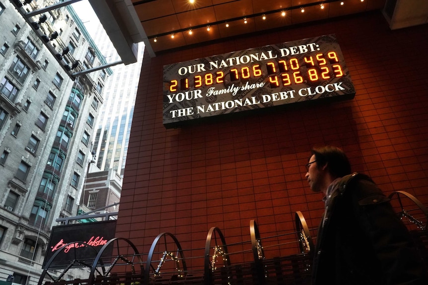 A man walks past the the National Debt Clock