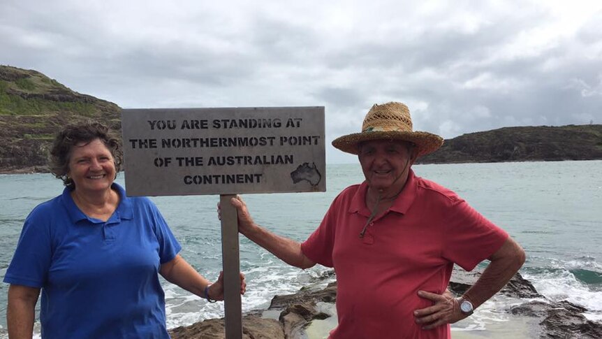 Pamela and Kevin Milner pose in front of sign by the sea in Cape York at the northernmost point of the Australian continent.