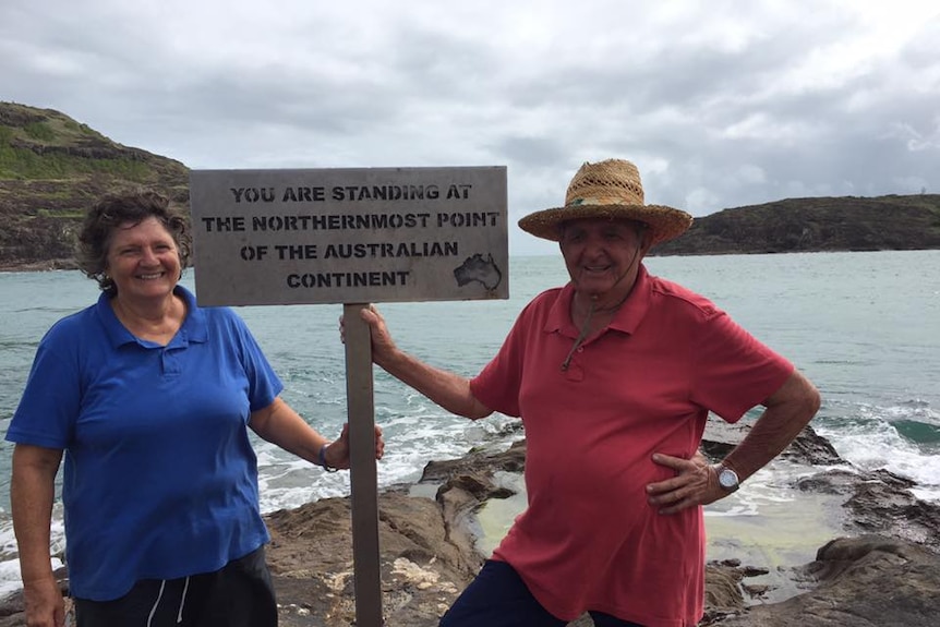 Pamela and Kevin Milner pose in front of sign by the sea in Cape York at the northernmost point of the Australian continent.