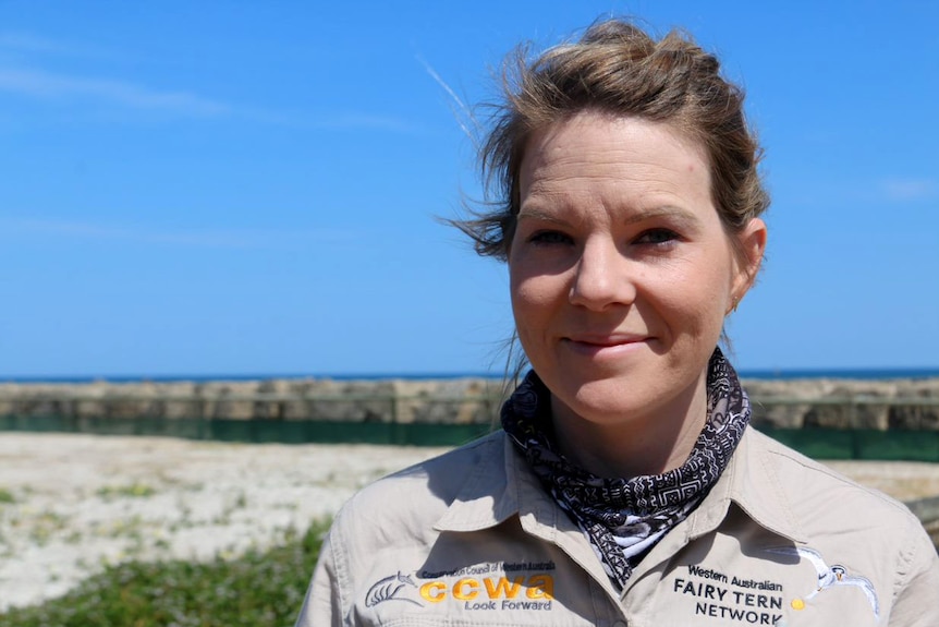 Headshot of a woman with ocean in the background.