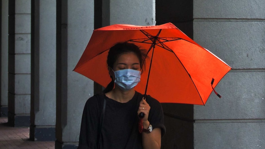Woman wearing face mask and holding an umbrella
