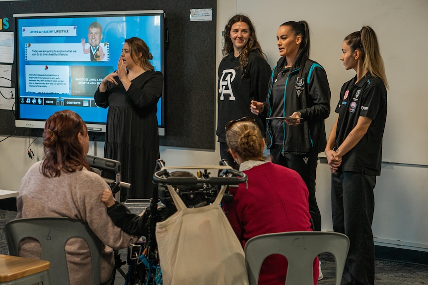 Four women stand in front of a class of hearing-impaired children at Brighton Primary School