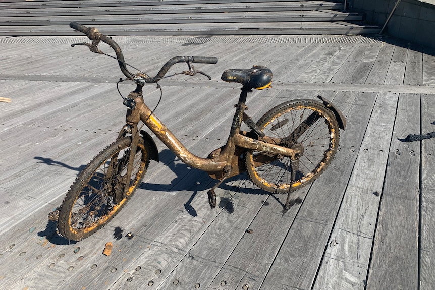 A rusted bike on a boardwalk.