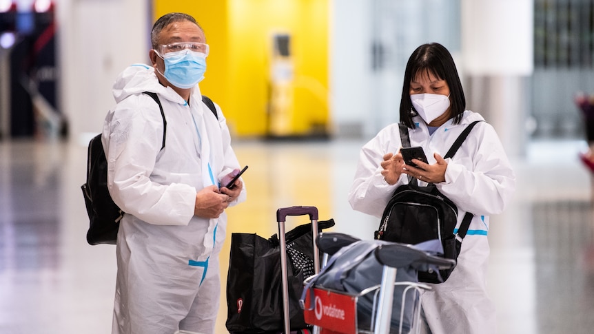 Un uomo e una donna in aeroporto con dispositivi di protezione individuale