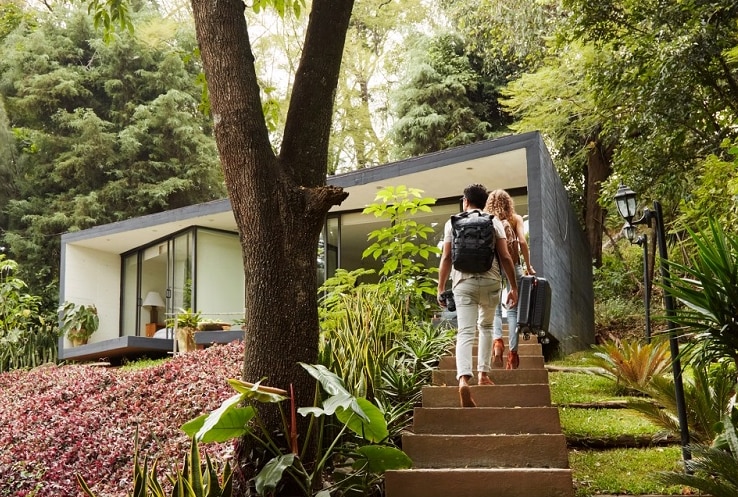 Unidentified couple walking towards accommodation carrying luggage.