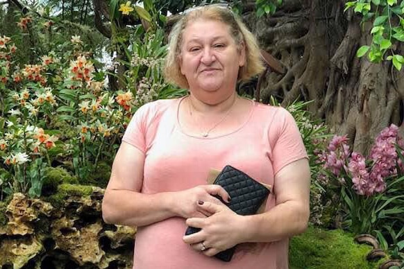 Marija Karovska standing in front of a flowering garden.