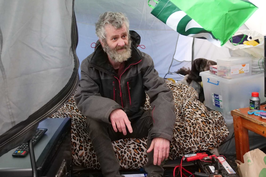 A man sits in a tent. 