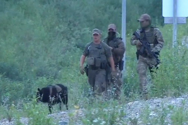 armed police officers walking through the wilderness