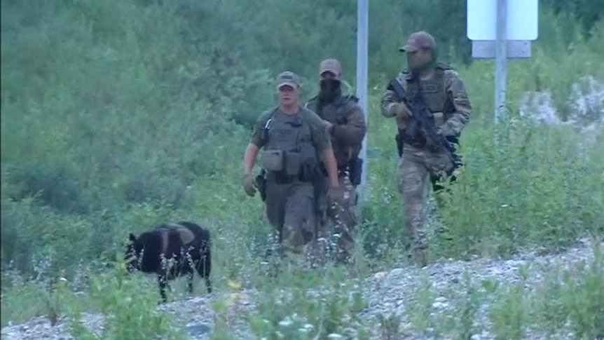 armed police officers walking through the wilderness