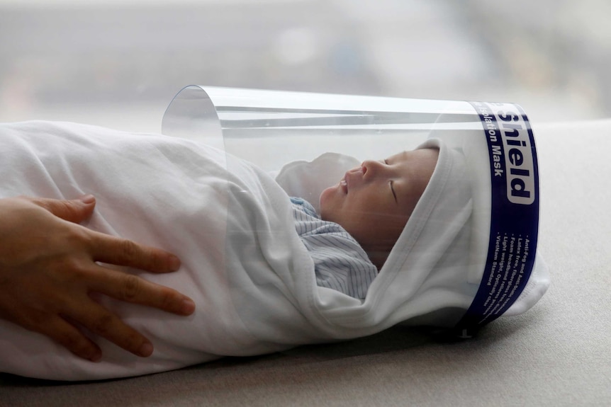 A newborn baby wears a protective face shield at a hospital in Hanoi.