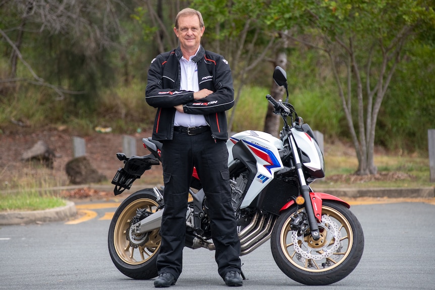 A man standing in front of a motorcycle.