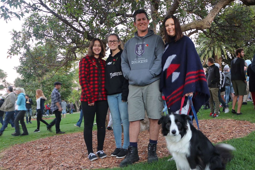 A couple stand with two teenage girls and a dog posing for a picture in Kings Park.