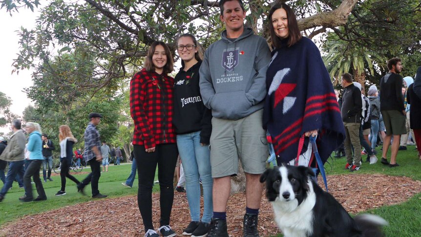 A couple stand with two teenage girls and a dog posing for a picture in Kings Park.