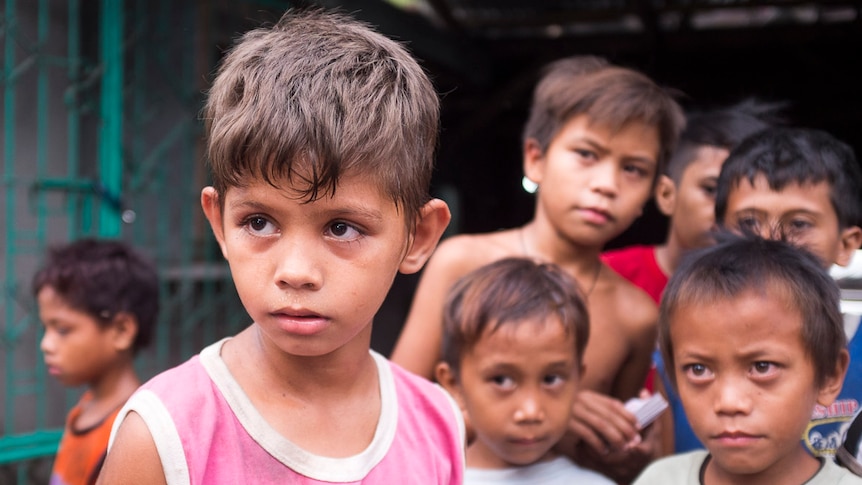 11 year-old child Kevin stares as other children from a slum in Angeles City, Philippines, look on. September 2016.