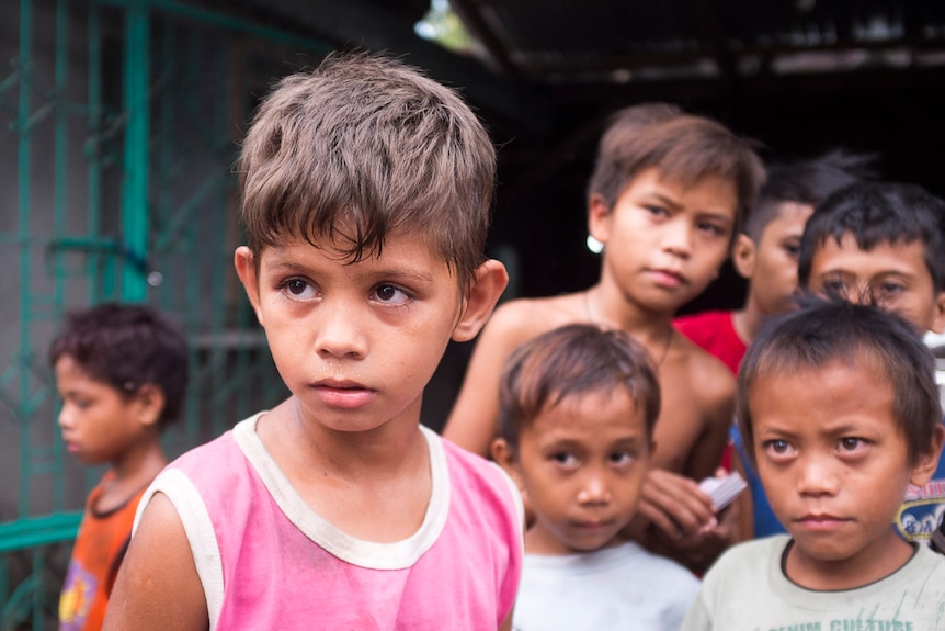 11 year-old child Kevin stares as other children from a slum in Angeles City, Philippines, look on. September 2016.