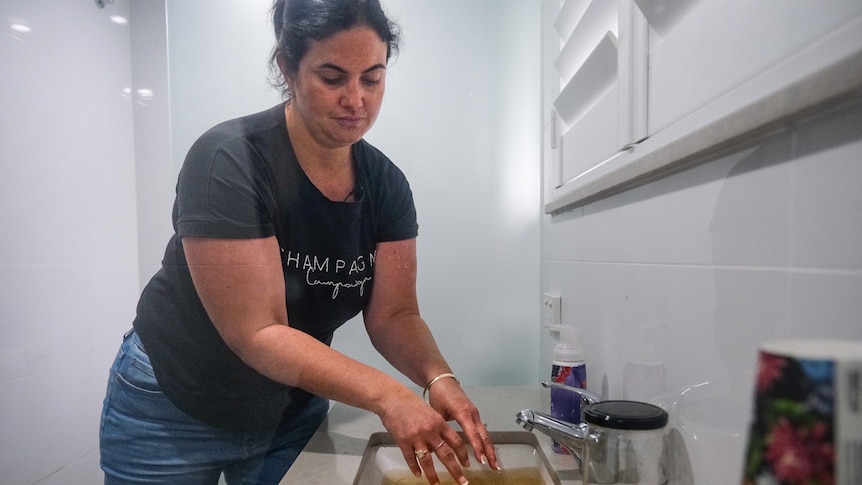 A woman standing over a sink washing her hands