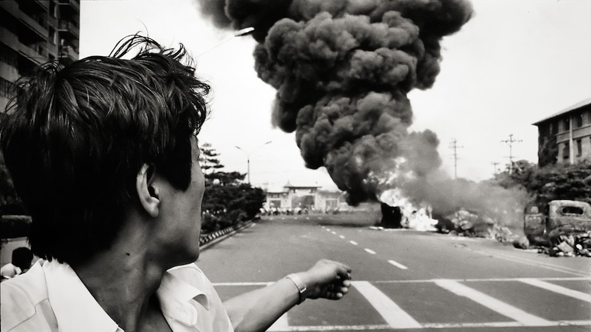 A man points towards a burning car in Beijing on June 4, 1989, the day of the Tiananmen Square massacre.