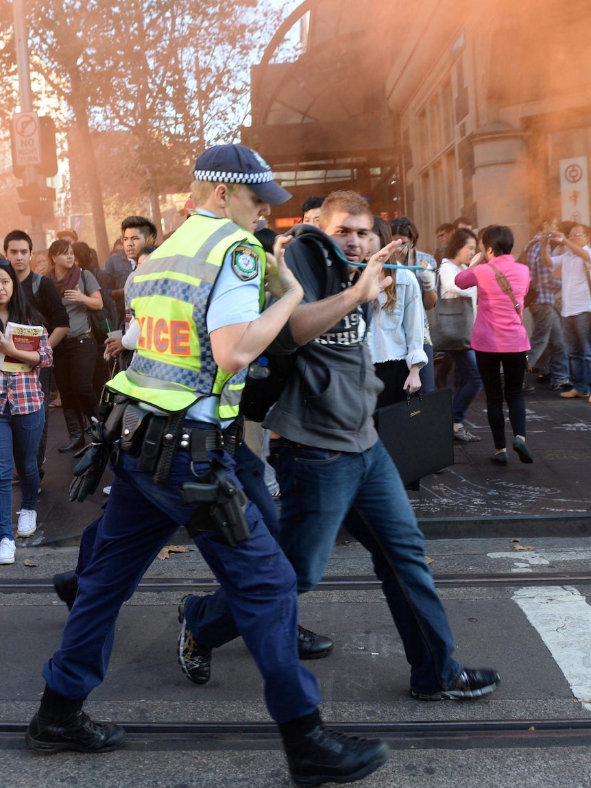 A protester is arrested as university students march through the Sydney CBD in protest.