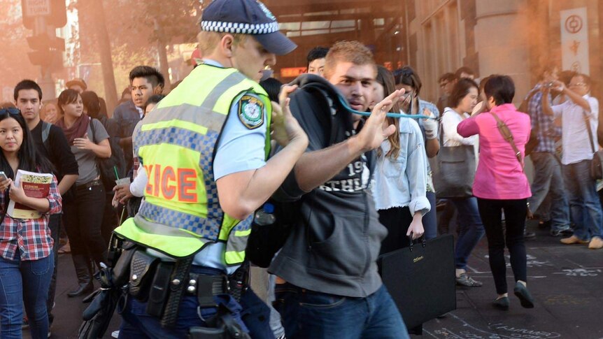 A protester is arrested as university students march through the Sydney CBD in protest.