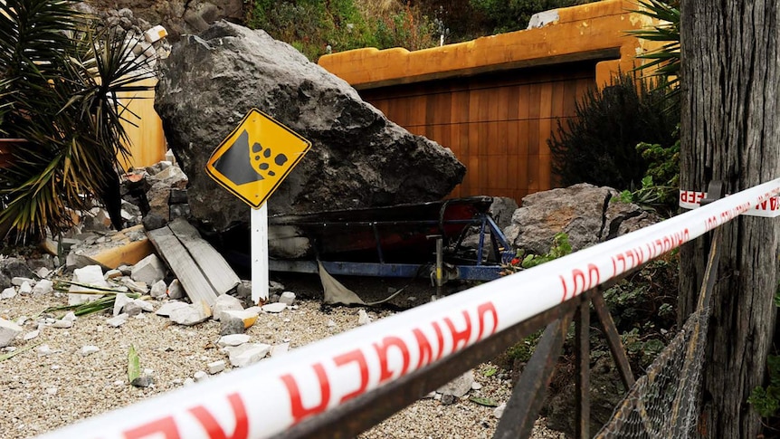 A broken 'falling rock' sign sits near a cliffside residence on February 25, 2011 after an earthquake.