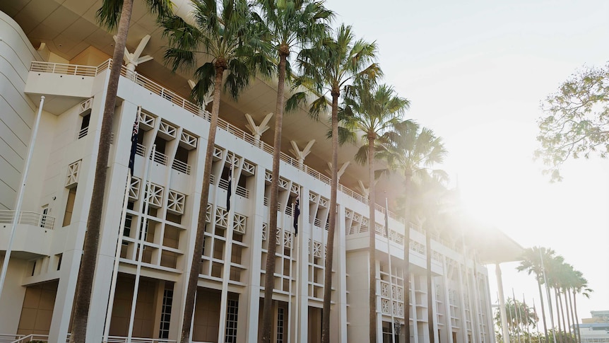 An exterior photo of Parliament House in Darwin. There are large palm trees out the front.