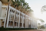 An exterior photo of Parliament House in Darwin. There are large palm trees out the front.