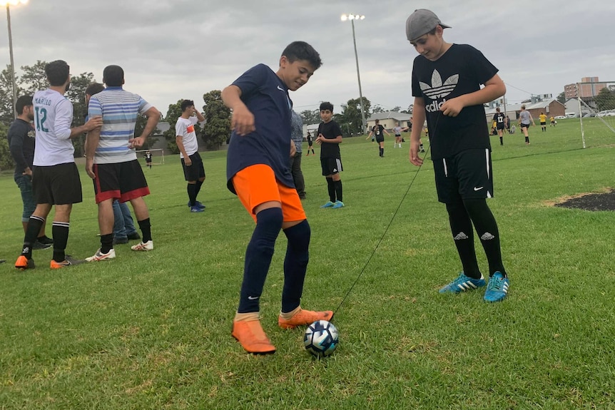 Two boys kicking a small ball