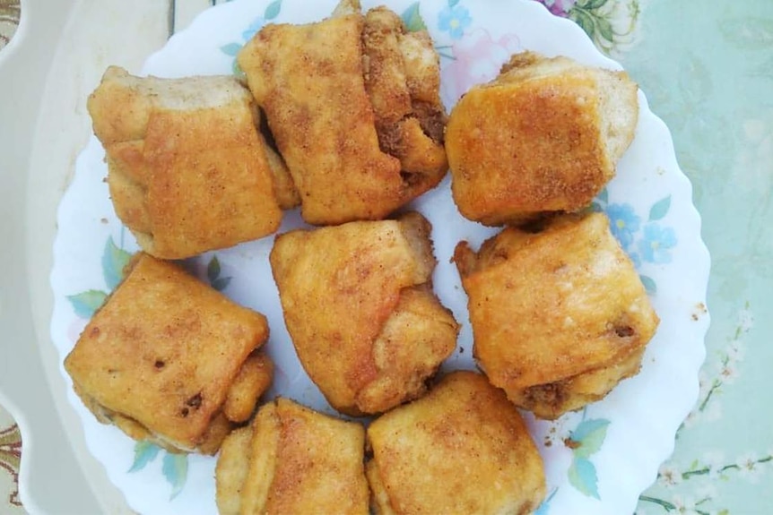 Eight pastries on a white plate. The pastries are called nokul and are made from crushed poppy seeds ground into a paste.