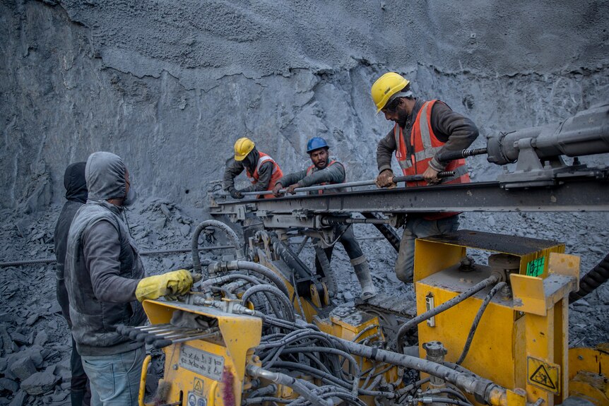 Workers prepare a machine for rock bolting