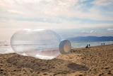 A giant inflatable bottle on a beach.