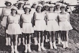 Black and white photo of girls in white top and skirt uniform