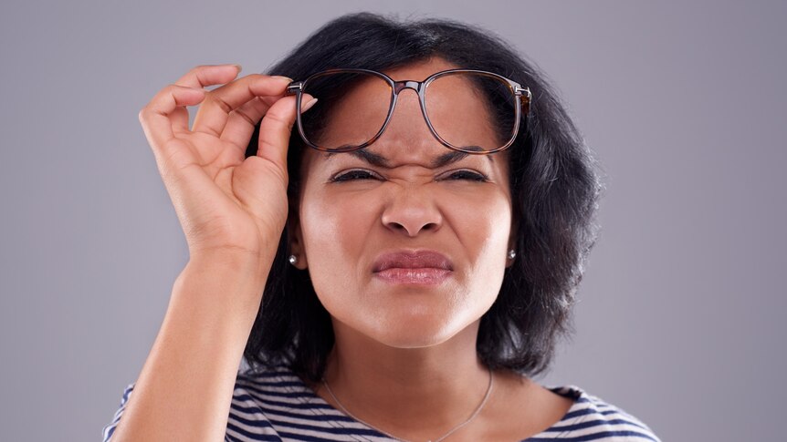 Woman squinting and checking her glasses