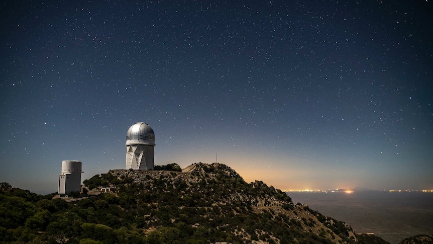 An Observatory and the sky with a city in the background.